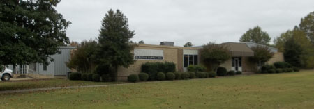 Single-story brick building with trees and lawn